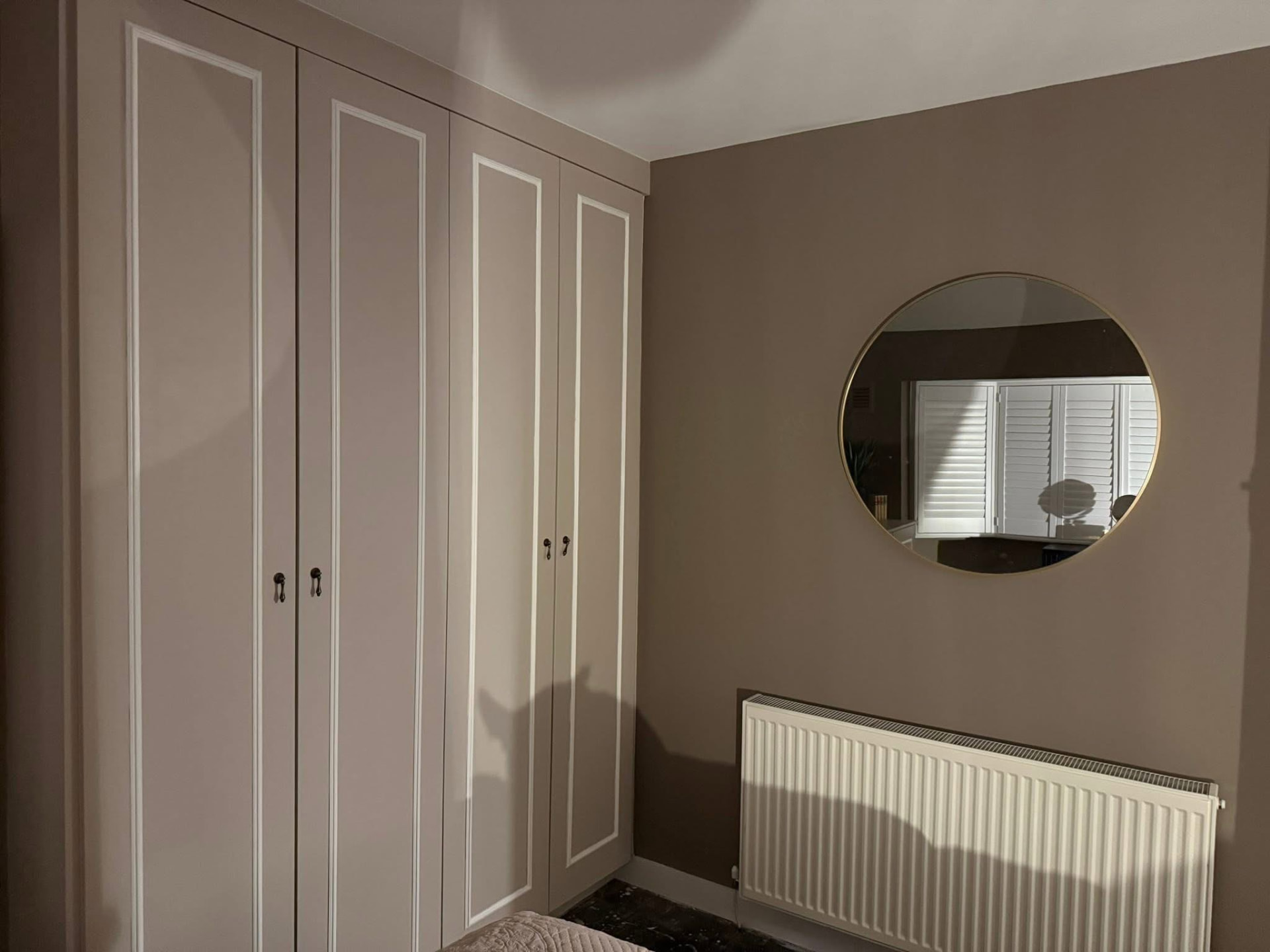 Hand-painted fitted wardrobes in soft mushroom with white beading against taupe bedroom walls