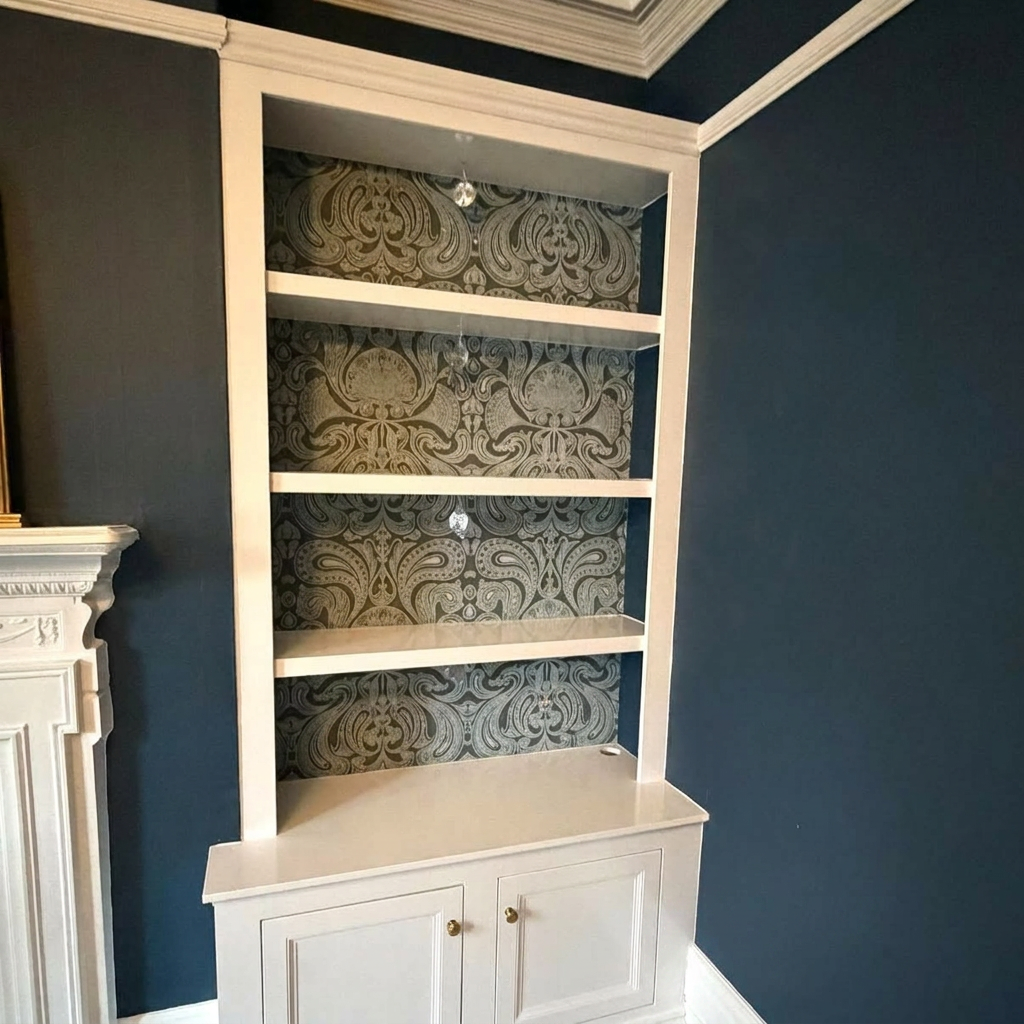 Hand-painted alcove cabinetry and shelving finished in crisp white against deep navy walls