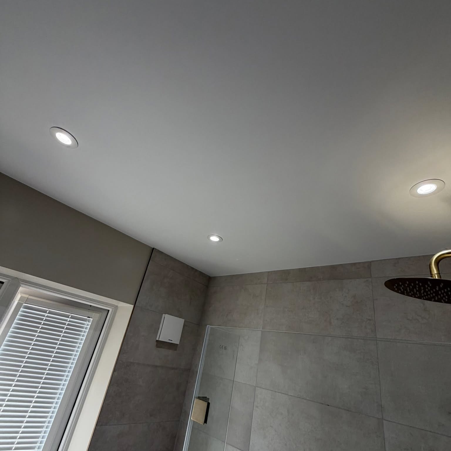 Shower room with grey tiling and freshly painted ceiling and walls