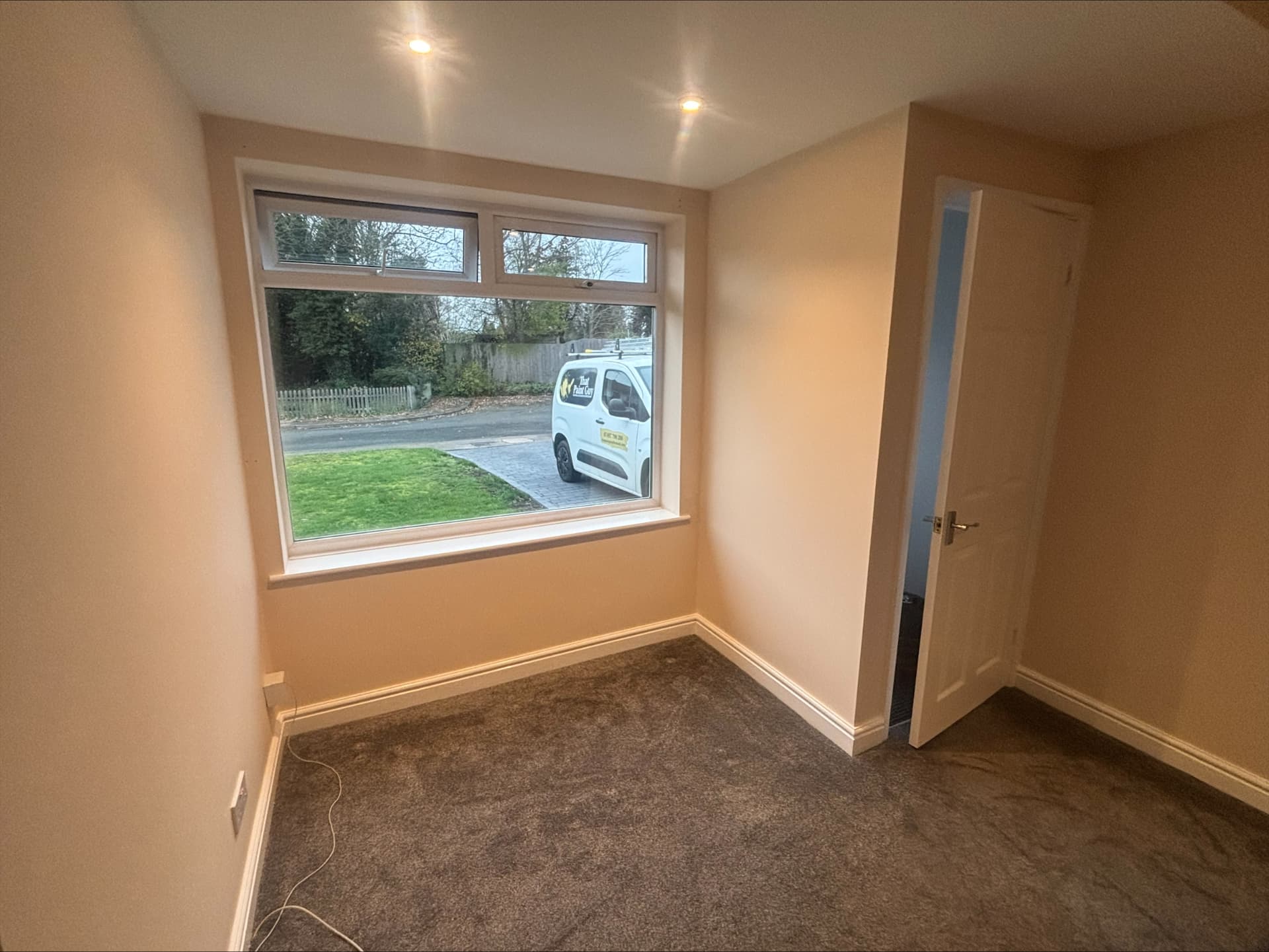 Small bedroom painted in warm blush with neatly cut-in window reveal and white skirtings
