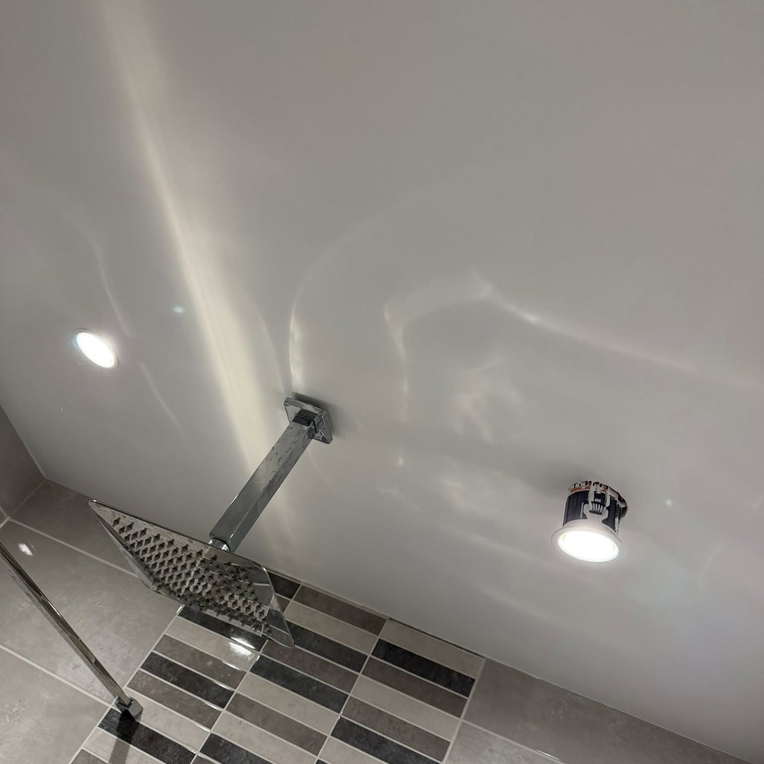 Shower room with chequered feature tiling and freshly painted sloped ceiling