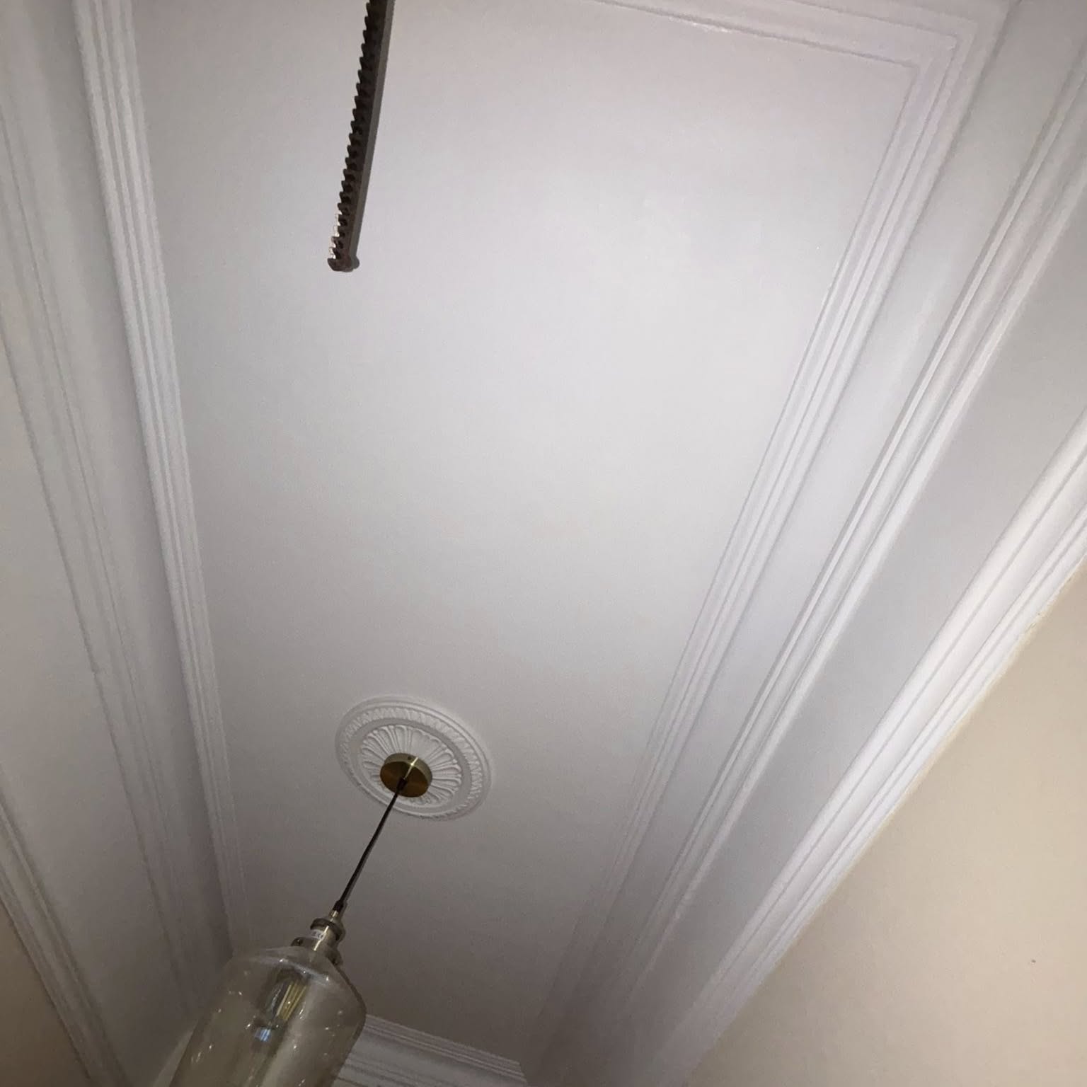 Freshly painted period ceiling with ornate ceiling rose, cornice and glass pendant