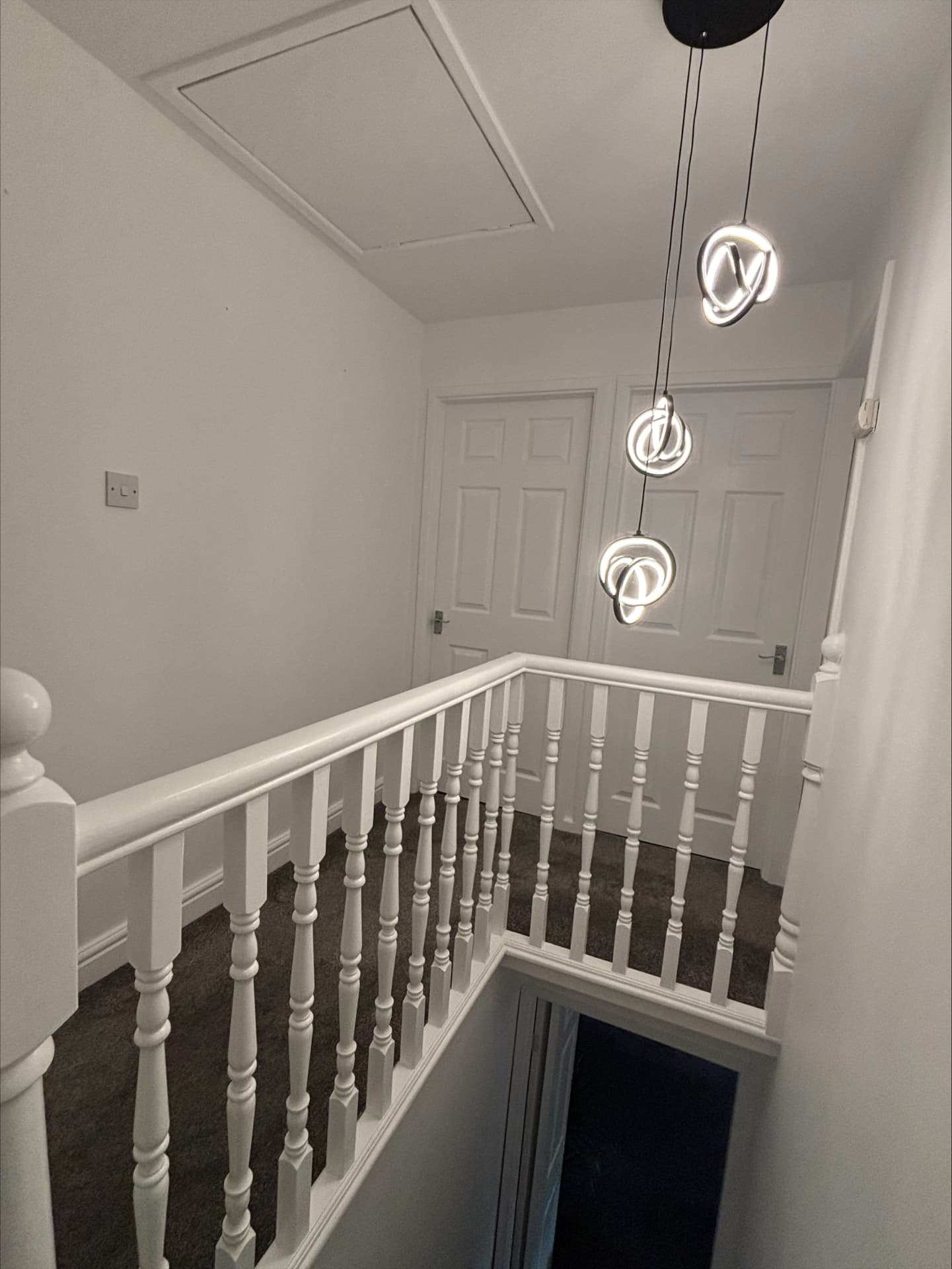 White stairwell and landing with gloss-finished balustrade, newel posts and panelled doors