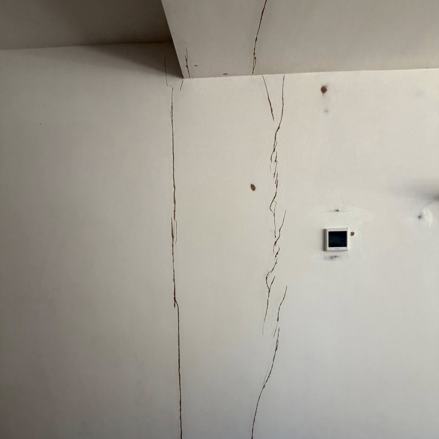 Settlement cracks in a plastered wall being prepared for filling