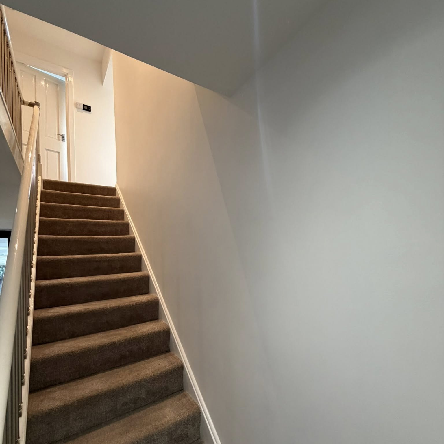 Staircase and landing with crisp white walls after a full repaint