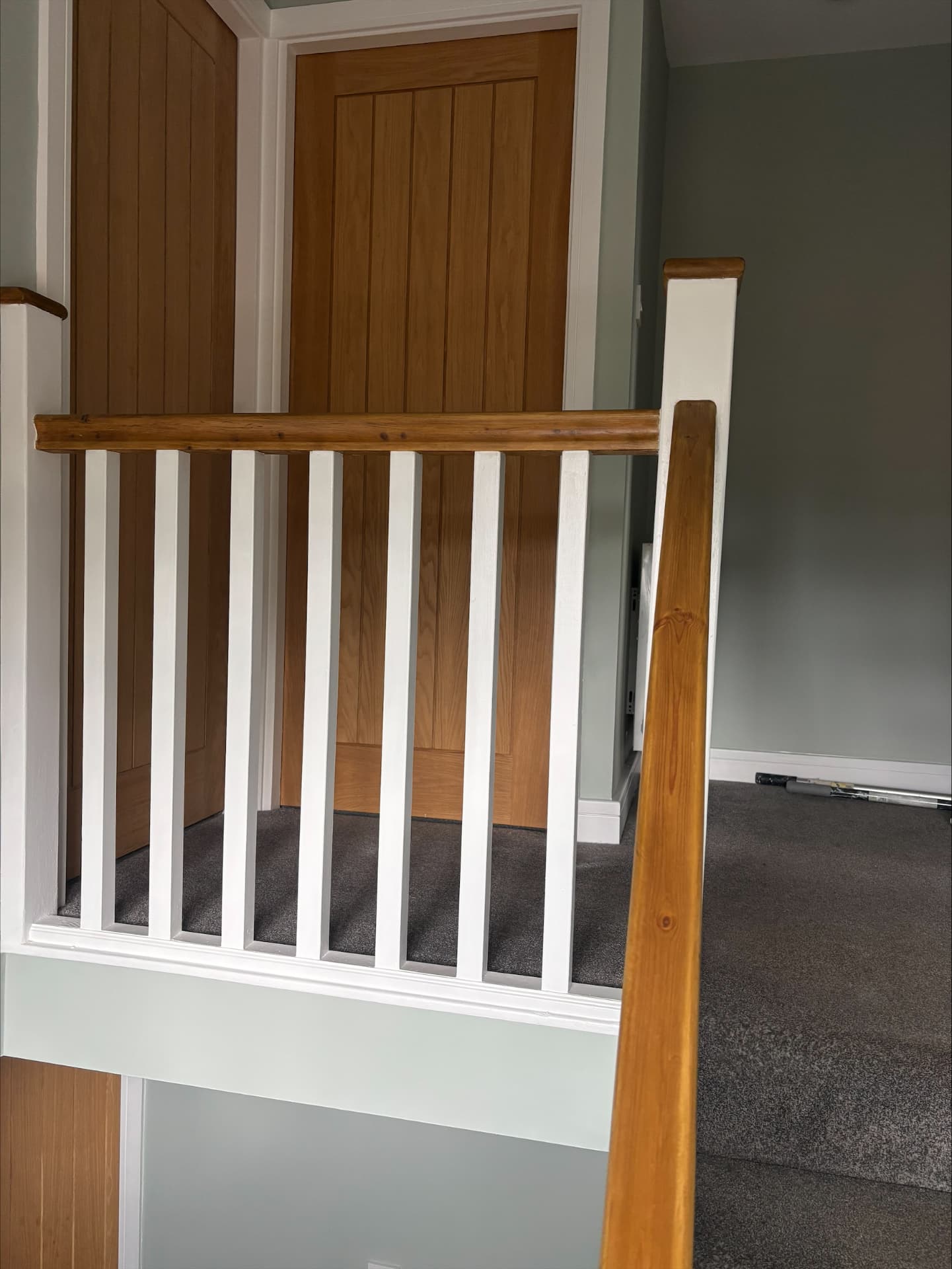 Landing with hand-painted white balustrade, oak handrail and sage green walls