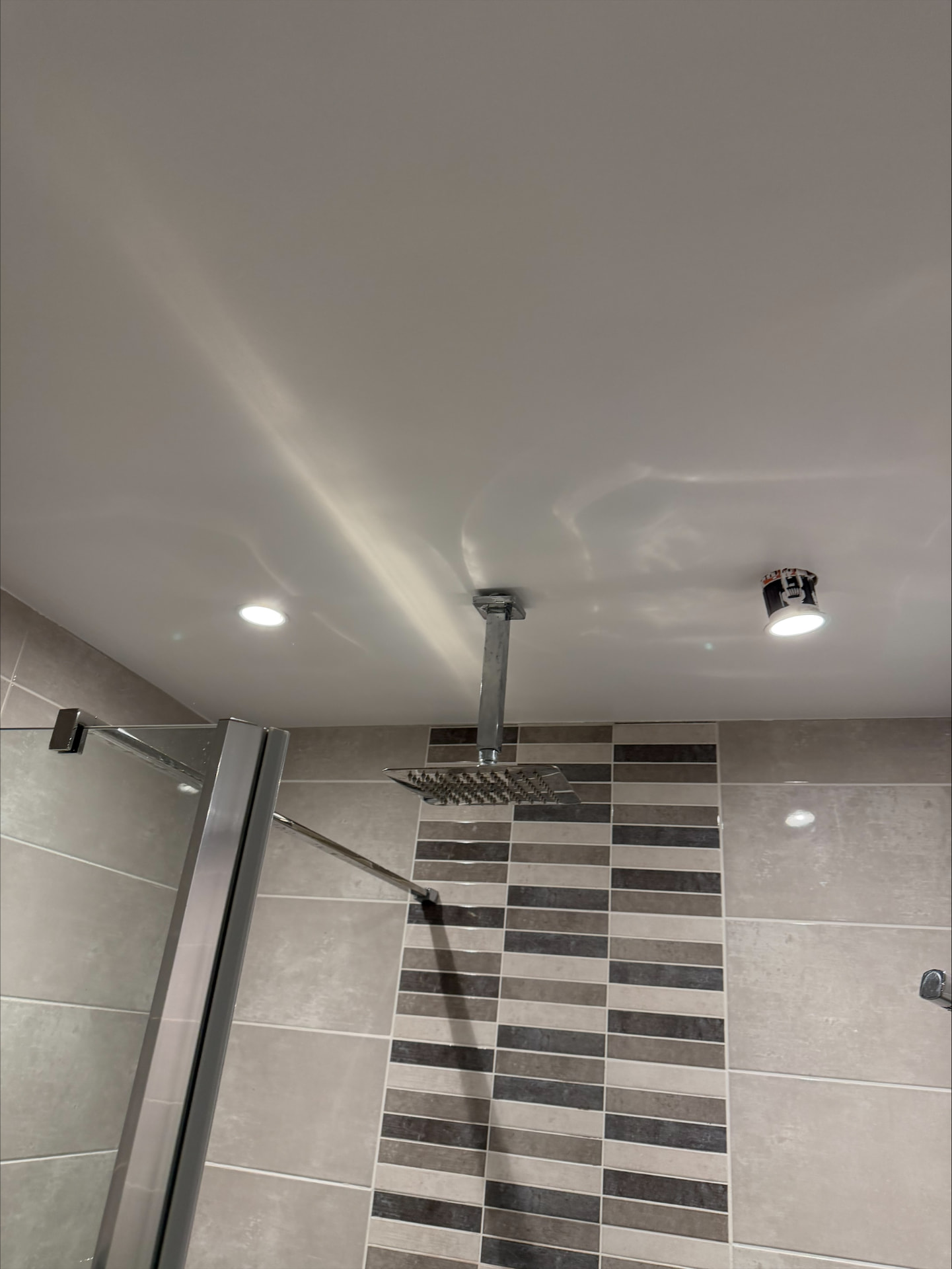 Freshly painted moisture-resistant shower room ceiling cut in neatly against grey tiling