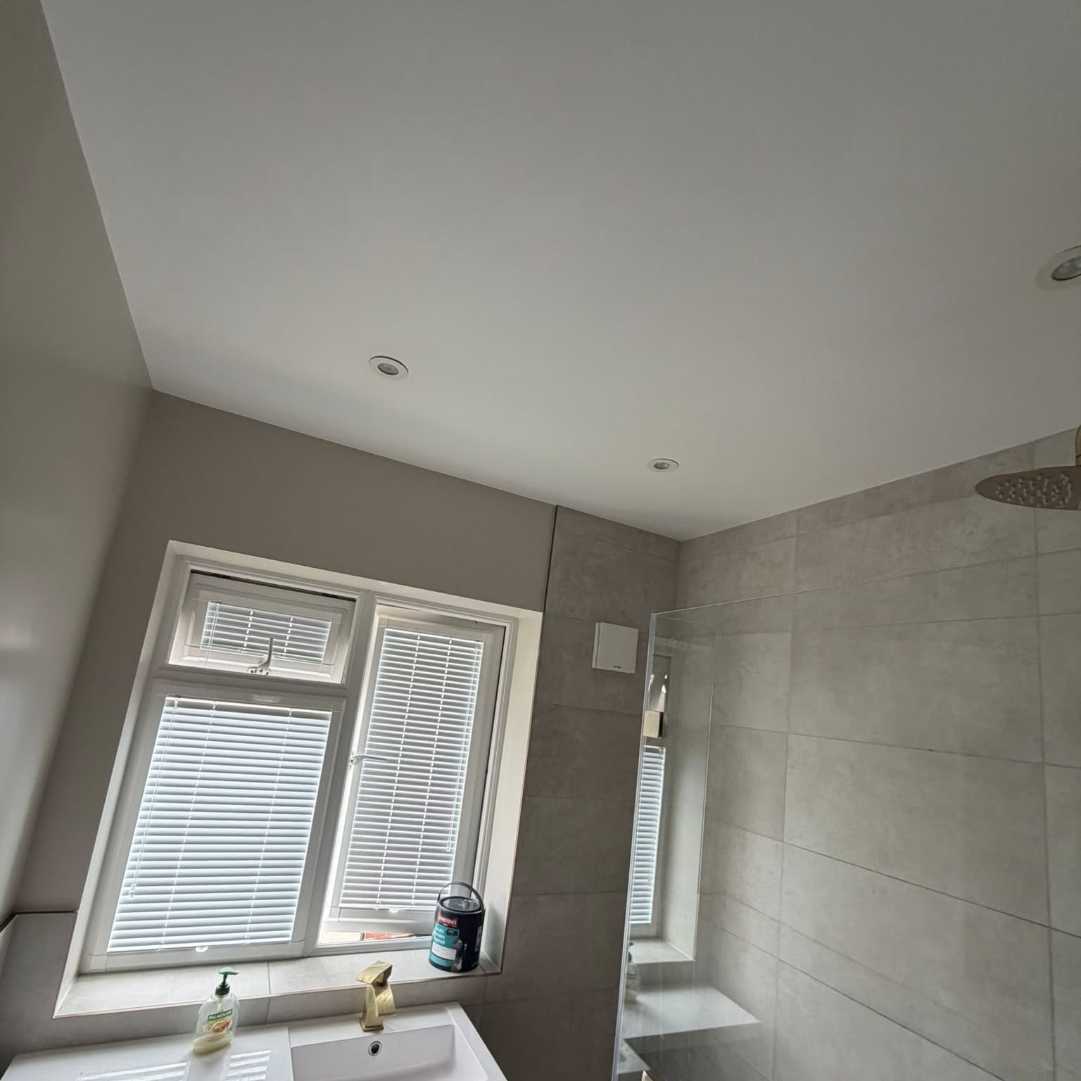 Tiled bathroom with freshly decorated ceiling and window wall