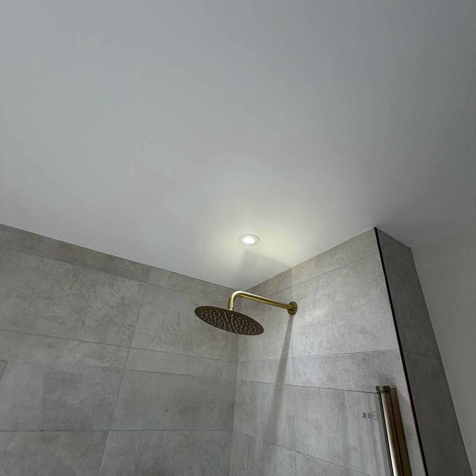 Modern bathroom with grey tiling and brushed gold shower after redecoration