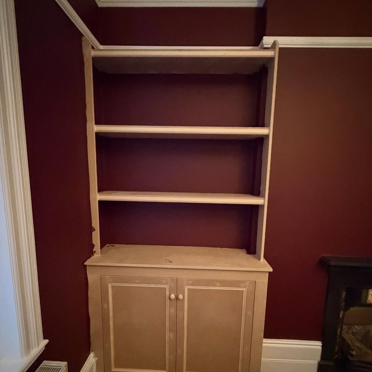 Alcove cupboard in unfinished oak before hand-painting against burgundy walls