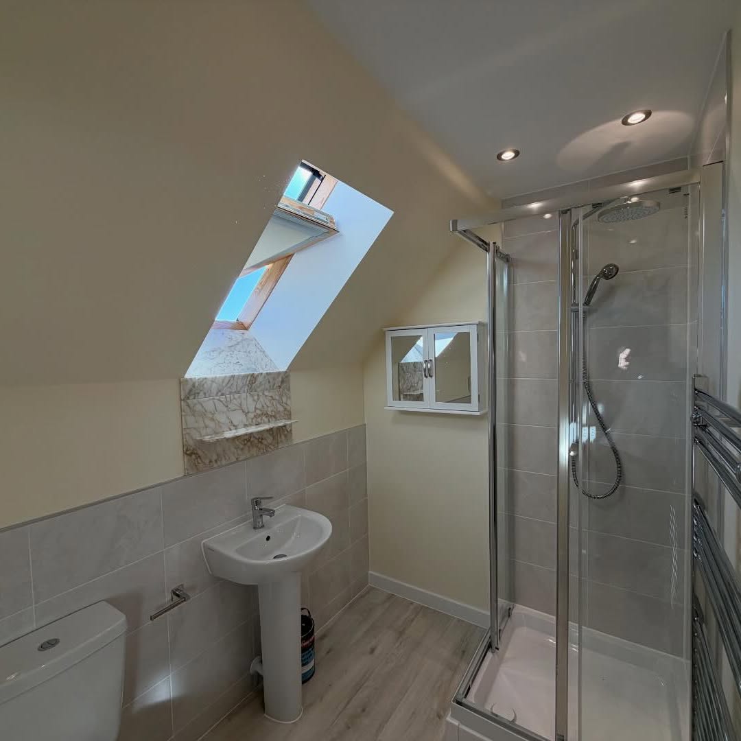 Loft shower room with sloped ceiling and freshly decorated walls