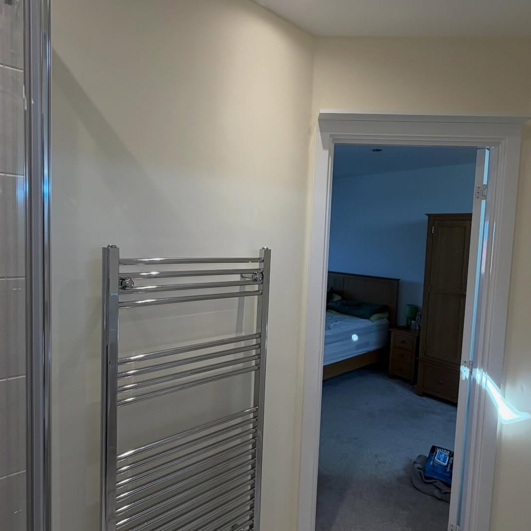 Freshly painted landing with chrome radiator looking into a decorated bedroom